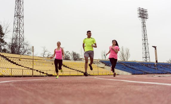 Three athlete people running in speed on sport ground