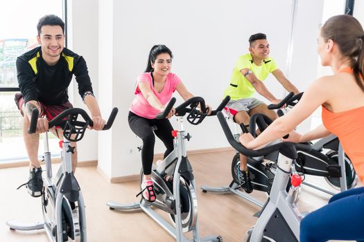 Group of young people cycling at gym