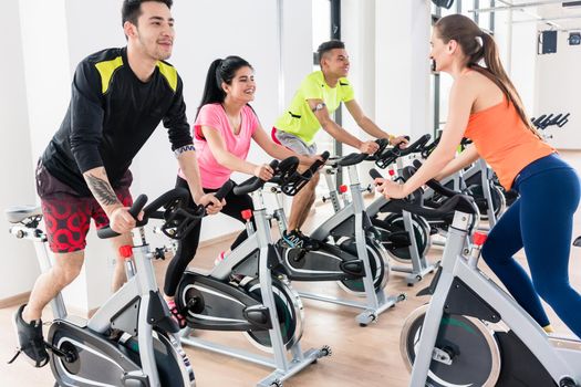 Active people exercising on bicycle at gym