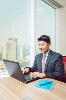 Smiling businessman using laptop in the office