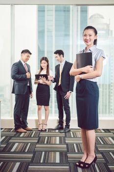 Smiling young businesswoman standing in front of colleague discussing on digital tablet