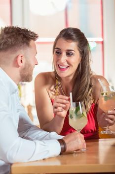 Portrait of happy young couple looking at each other while having cocktails