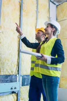 Construction manager and architect checking the insulation works in a half finished project