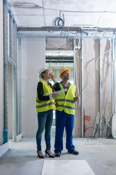 Construction worker and architect discussing work to be done at site to finish the building