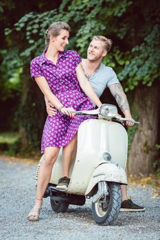 Young woman sitting on her boyfriend's lap sitting on scooter