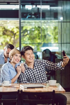 Portrait of smiling young couple taking selfie on cellphone sitting in the cafe