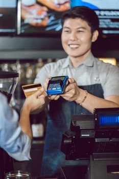 Close-up of customer making wireless payment using credit card in the coffee shop