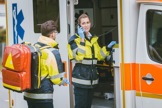 Medics in front of ambulance talking to headquarters using radio communication