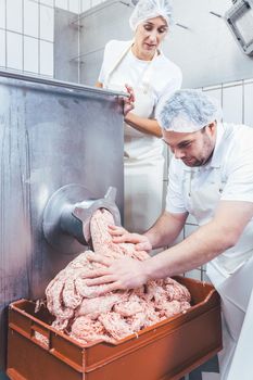 Butcher grinding meat with machine in butchery