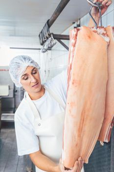 Butcher woman cutting meat for further use and processing