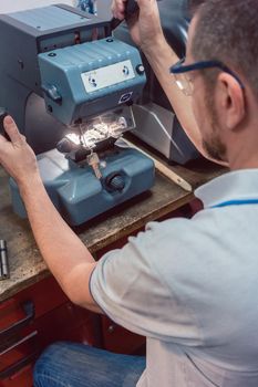 Skilled locksmith cutting key with his machine