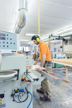 Carpenter working in furniture factory on computer controlled machine