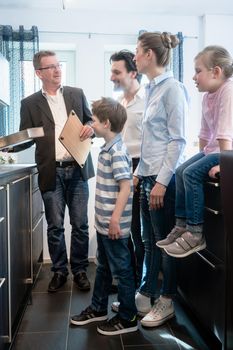 Experienced salesman showing family the features of a new kitchen