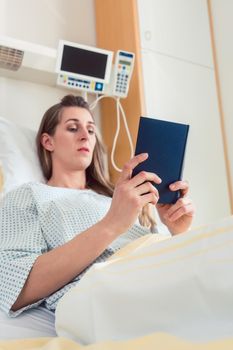 Woman in hospital bed reading the bible to find consolation