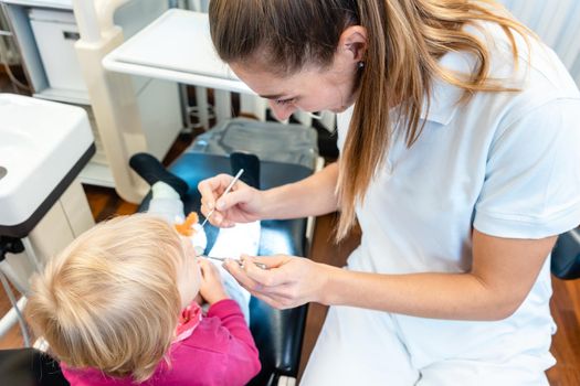 Woman dentist looking after teeth of a child in her surgery