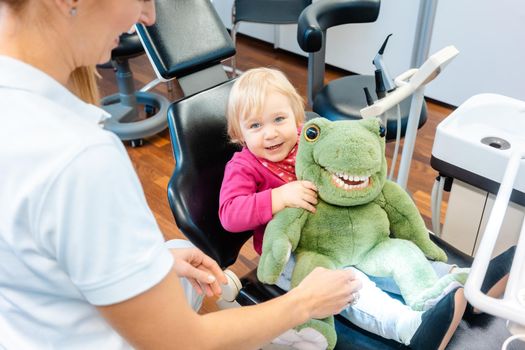 Little girl having fun with plush toy visiting the dentist