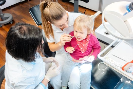 Woman dentist looking after baby teeth of a little girl in her surgery
