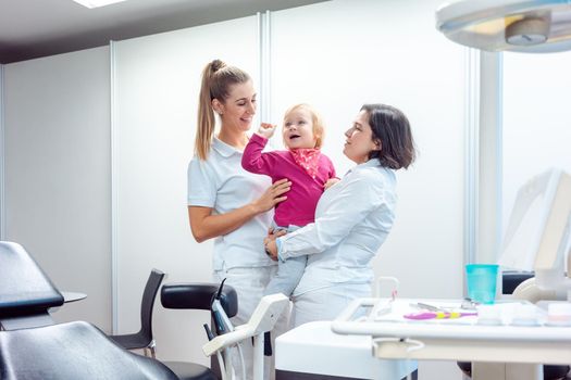 Playful dentist and her assistant with child in the office