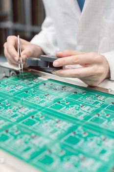 Technician inserting electronic components into a PDB for assembly of an electronic product