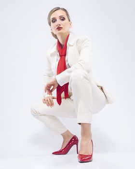 Fashion business model wearing a bold white suit and red accessories, studio shot