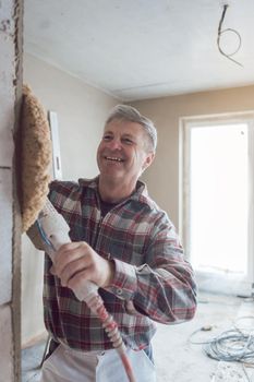 Plasterer man smoothing interior wall of new homes with machine