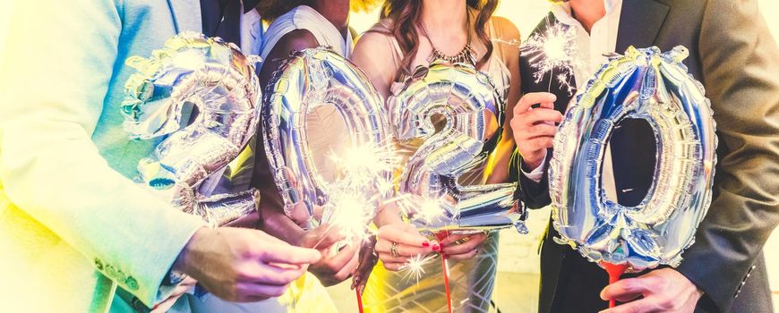 Men and women celebrating the new year 2020 with sparklers and wine