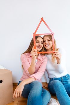 Two women having rented a new apartment moving in looking thru folding rule