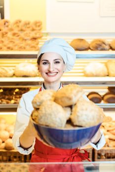 Fresh bread rolls presented by an attractive young sales woman in bakery