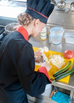 A female chef slicing cauliflower on a yellow chopping board in pieces for a meal