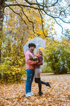 Man and woman of different ethnicity hugging in fall during a walk