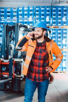 Worker in logistics warehouse on the phone receiving instructions