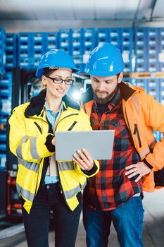 Woman and man as workers in logistics center using computer checking data