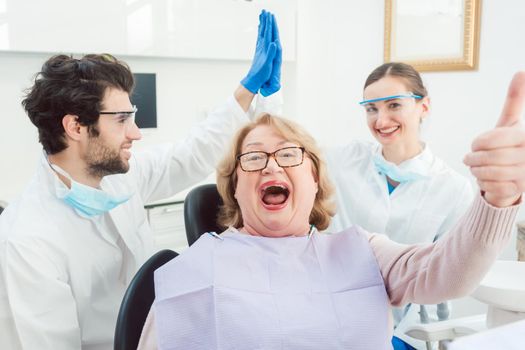 Dentists and patient in surgery being a bit over the top excited giving high five