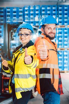 Workers in logistics distribution center showing thumbs-up after having a success