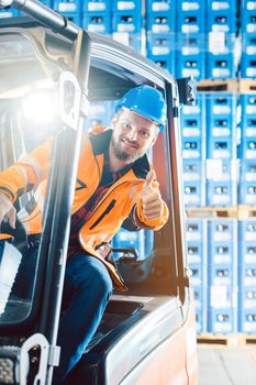 Successful worker showing thumbs up in logistics delivery center