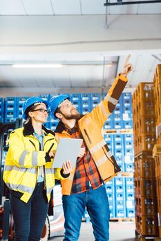 Workers in a logistics warehouse planning the next project using data supplied on a tablet computer