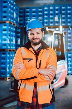 Worker in a forwarding company with his forklift looking into the camera