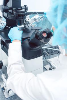 Woman doctor working in medical lab with manipulator and microscope