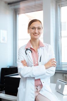 Smiling doctor woman standing at desk in her office