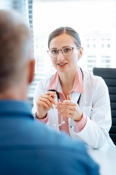 Beautiful doctor with male patient in her office listening