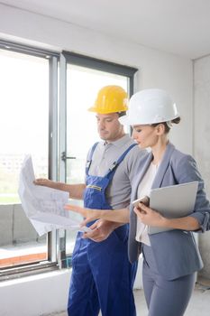 Construction worker and architect looking at plan or blueprint on site