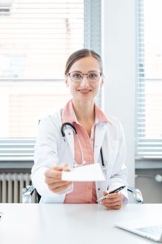 Female doctor holding prescription paper into the camera