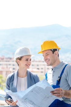 Principal and builder reading blueprints or building plans on construction site