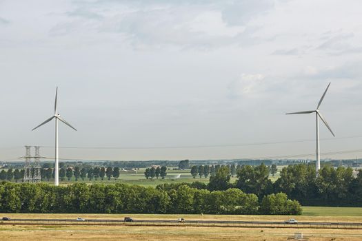Windmills as wind turbine power generators placed within the countryside of green country of Netherlands.