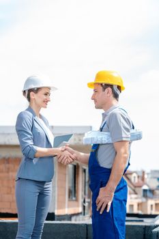 Handshake on construction site between developer and builder as acceptance of the work done