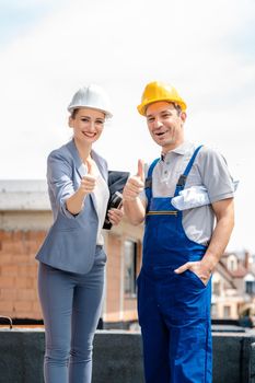 Architect and Construction worker on site giving thumbs-up to the camera