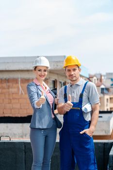 Architect and Construction worker on site giving thumbs-up to the camera