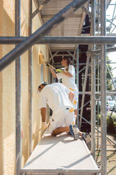 Two painters working diligently on scaffold on site