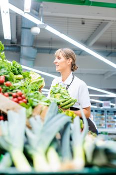 Woman working in a supermarket sorting fresh fruit and vegetables