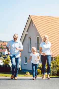 Happy family running in front of their new home in the village